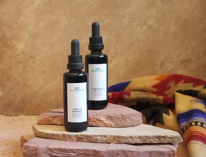 two bottles of skincare product placed on stair step rocks with desert background